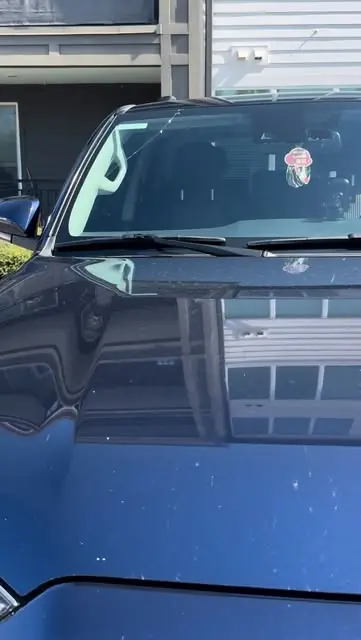 Blue car with a freshly replaced windshield in an apartment parking lot